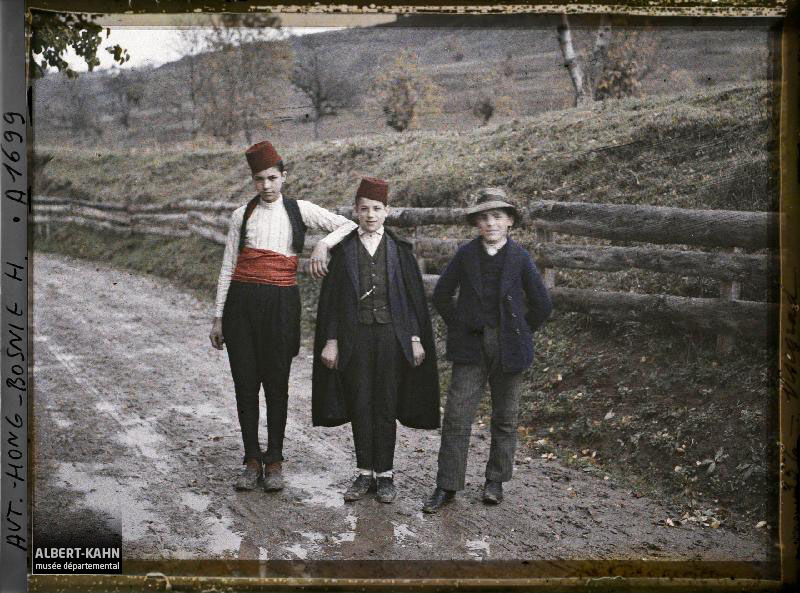 Bosnie, Višegrad, 3 Jeunes gens sur la route; les 2 à droite avec fez musulman, 3e à gauche avec chapeau Serbe